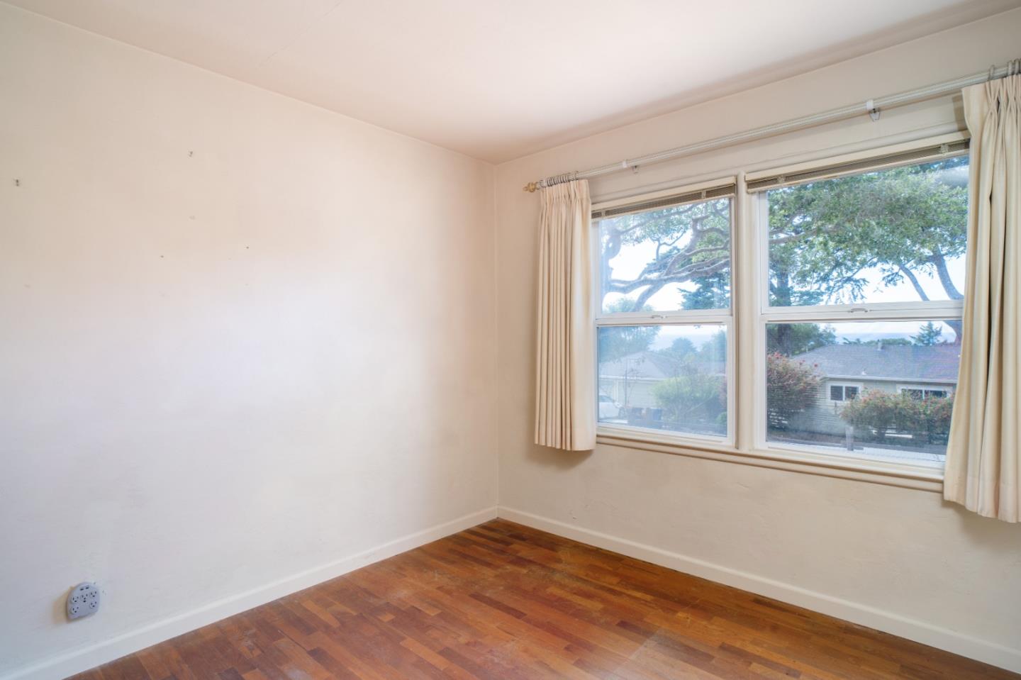 305 Stuart Avenue Pacific Grove, CA 93950 - Photo 12 of 24 an empty room with wooden floor and windows