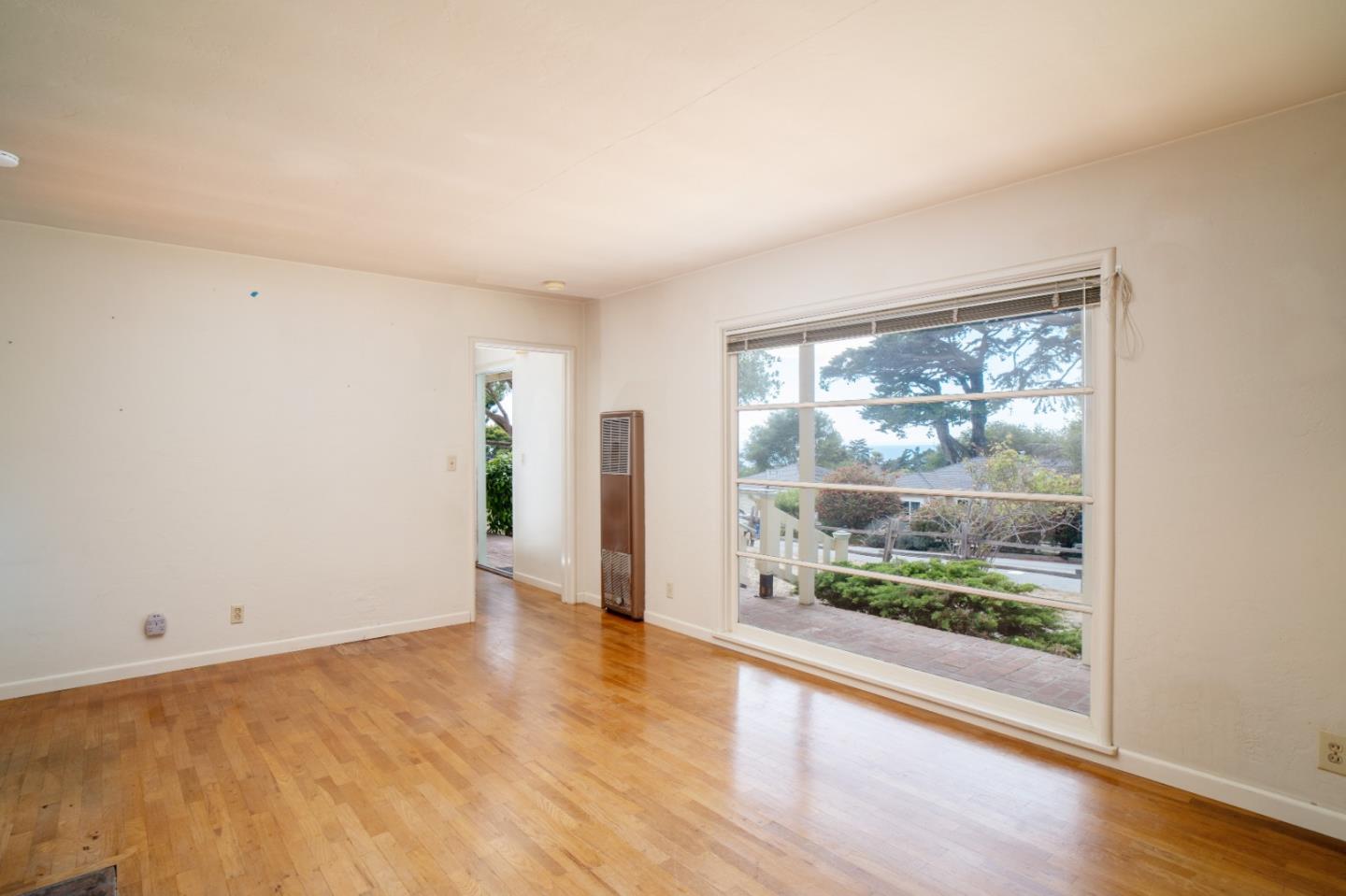 305 Stuart Avenue Pacific Grove, CA 93950 - Photo 5 of 24 a view of an empty room with wooden floor and a window