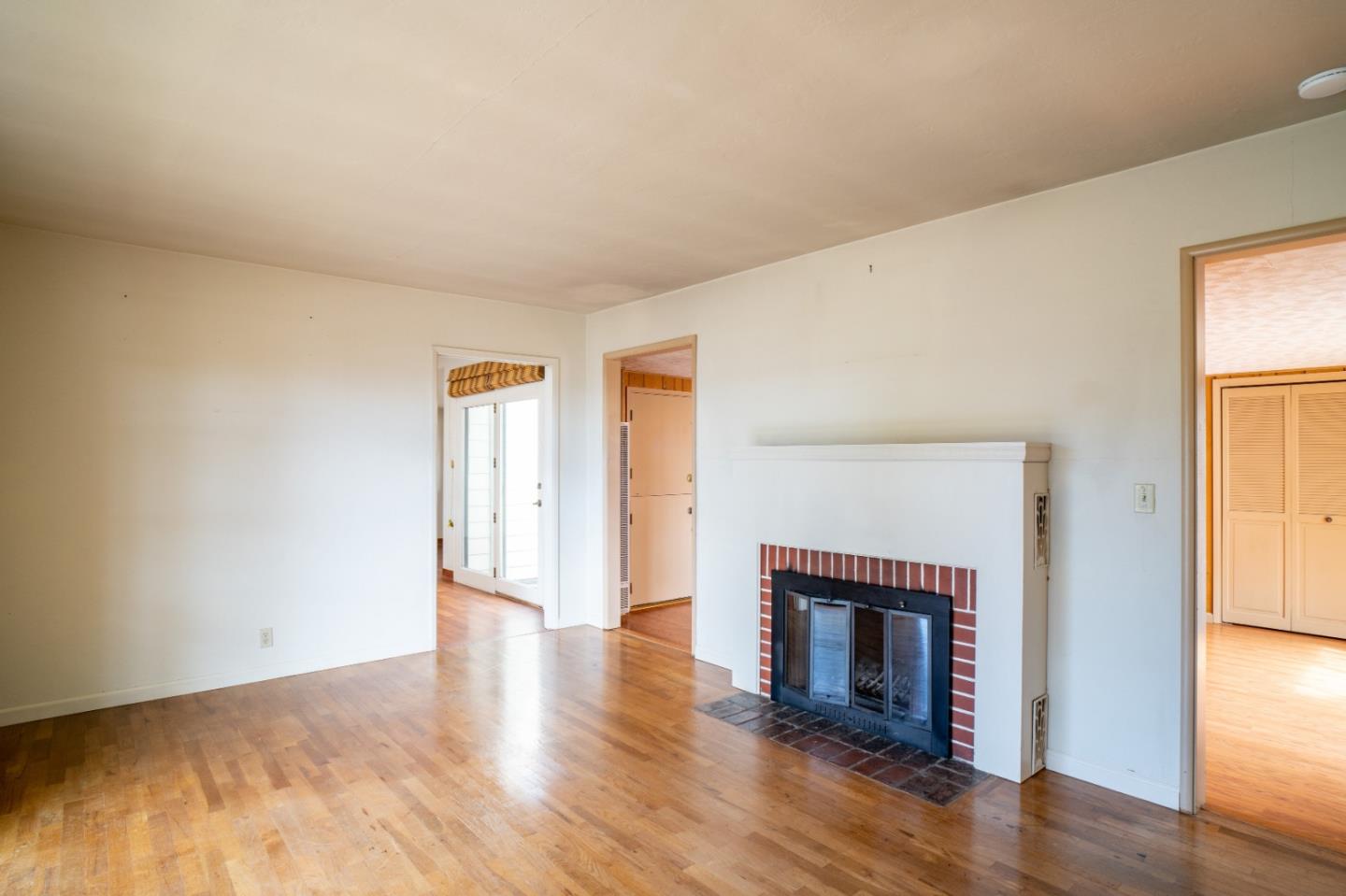 305 Stuart Avenue Pacific Grove, CA 93950 - Photo 6 of 24 an empty room with wooden floor fireplace and windows