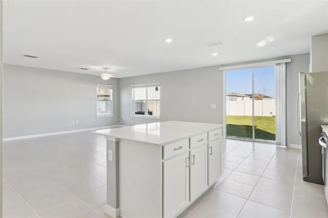a kitchen with kitchen island a sink a stove a refrigerator and white cabinets