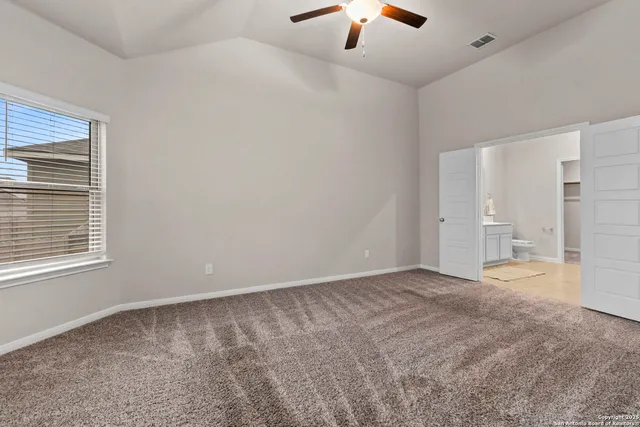 an empty room with chandelier fan and windows