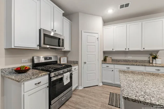 a kitchen with stainless steel appliances granite countertop a stove a sink and a white cabinets