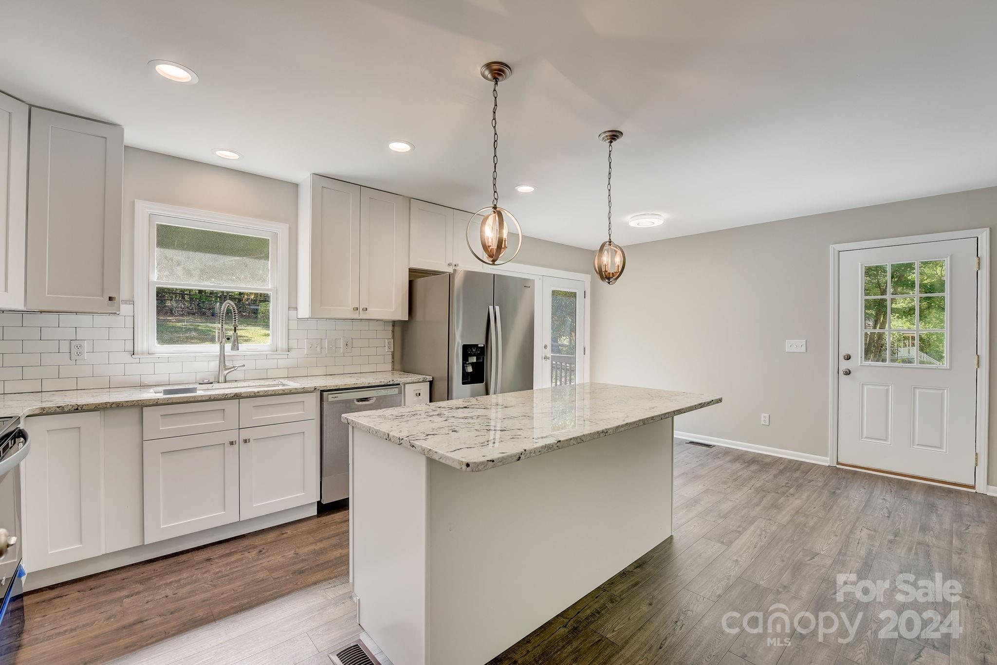 16218 Barbee Road Stanfield, NC 28163 - Photo 14 of 48 a kitchen with stainless steel appliances kitchen island a sink dishwasher a refrigerator and a wooden floor