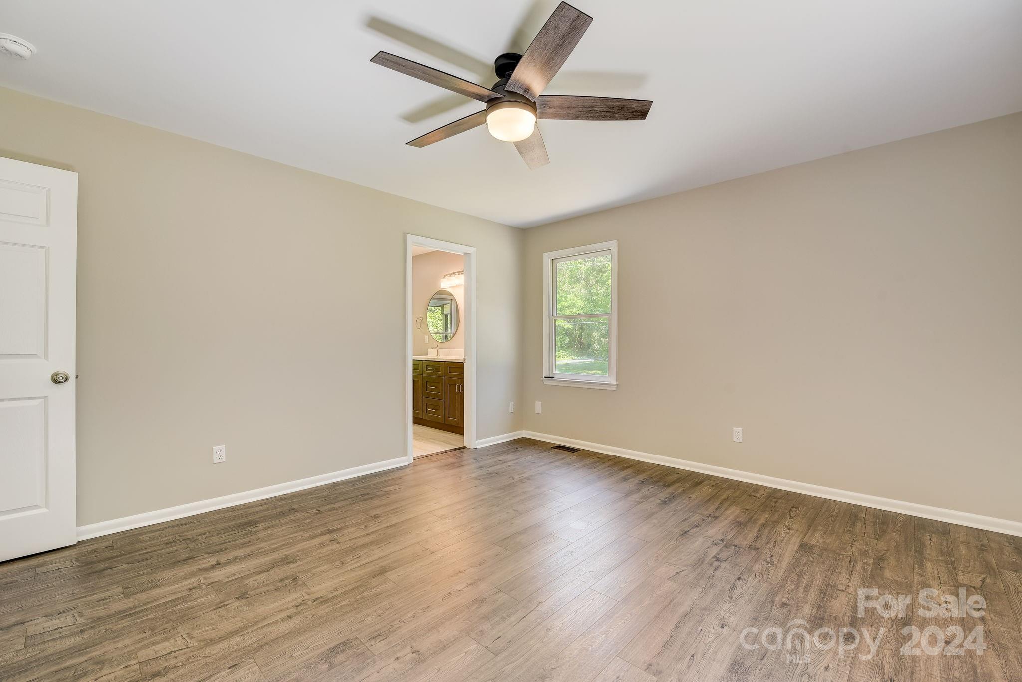 16218 Barbee Road Stanfield, NC 28163 - Photo 22 of 48 an empty room with wooden floor chandelier fan and windows