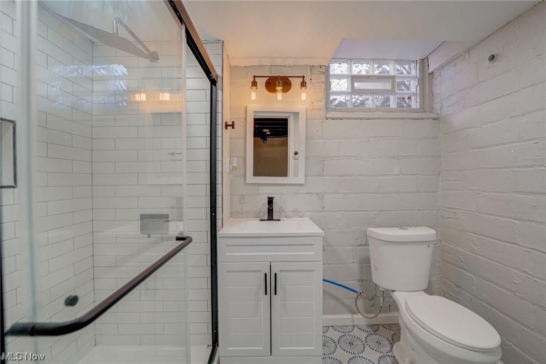6197 Turney Road Cleveland, OH 44125 - Photo 22 of 35 Bathroom featuring oversized vanity, brick wall, toilet, and an enclosed shower