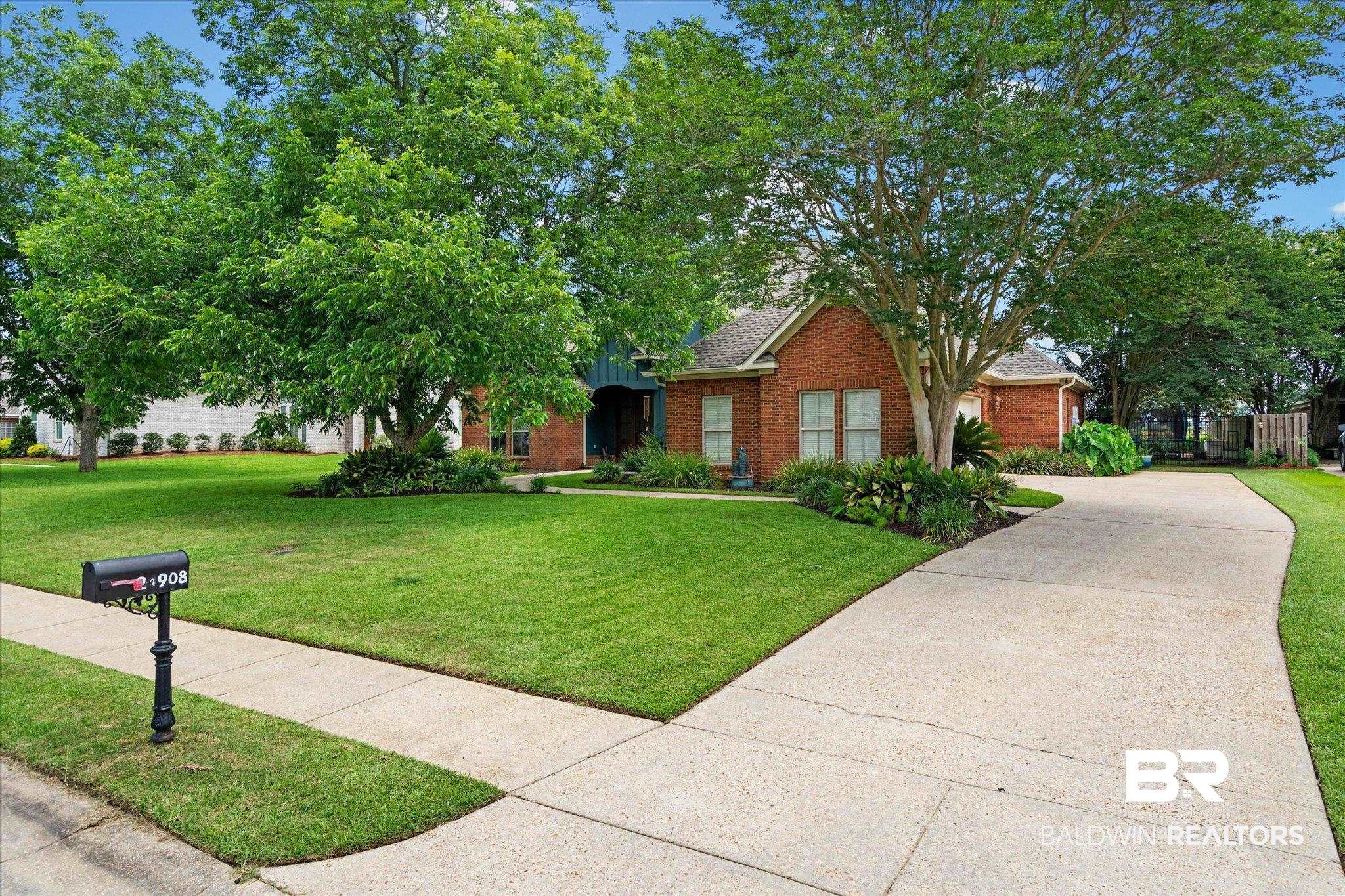 24908 Bosbyshell Avenue Daphne, AL 36526 - Photo 45 of 49 Brick facade home featuring a manicured lawn, established shade trees, a concrete driveway, and front landscaping