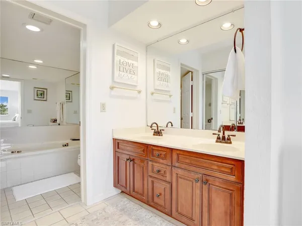 a bathroom with a sink double vanity granite tub shower and a mirror