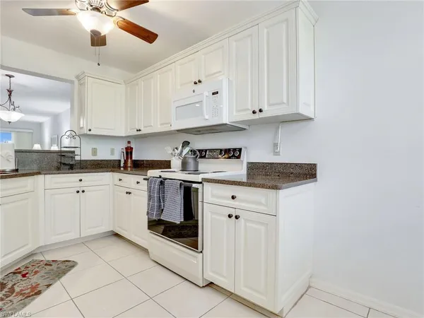 a kitchen with granite countertop white cabinets and white appliances