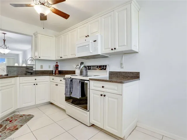 a kitchen with granite countertop white cabinets and white appliances