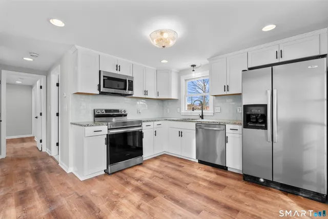 a kitchen with stainless steel appliances granite countertop a refrigerator a stove a sink and a microwave