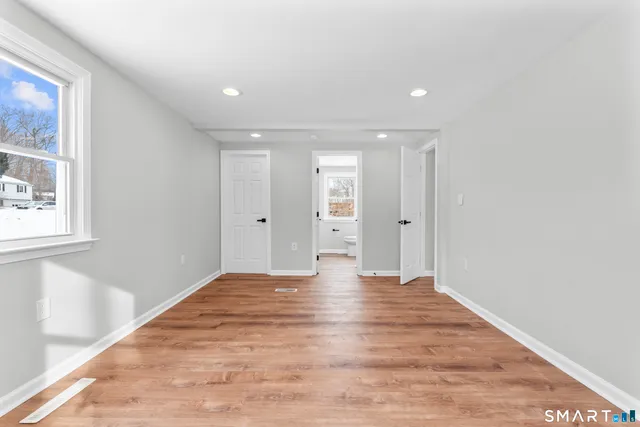 a view of an empty room with wooden floor and a window