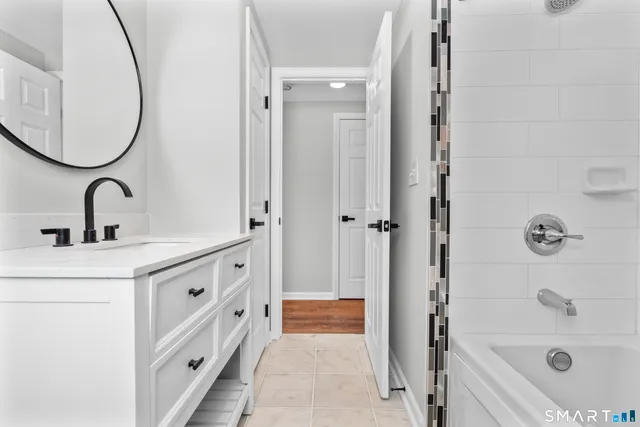 a bathroom with a tub sink and mirror
