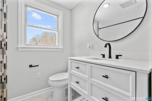 a bathroom with a toilet a sink and mirror