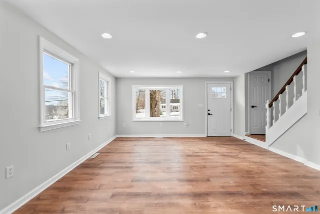 a view of an empty room with a window and wooden floor