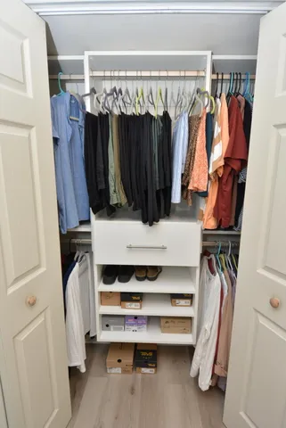 a view of walk in closet with clothes and shoes