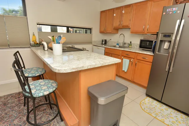 a kitchen with stainless steel appliances granite countertop a sink a stove a refrigerator a microwave oven with a dining table and chairs