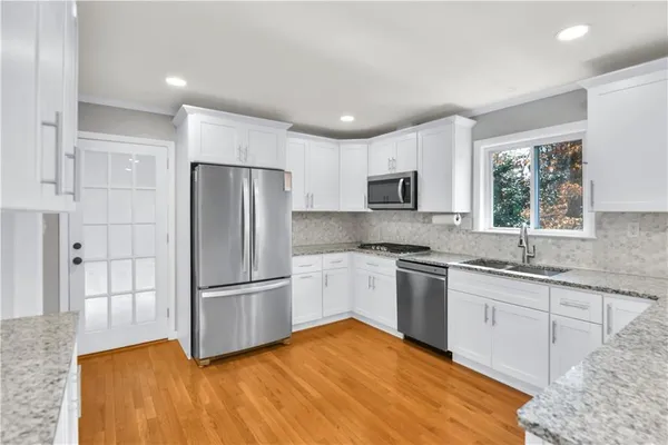 a kitchen with granite countertop stainless steel appliances a refrigerator sink and microwave