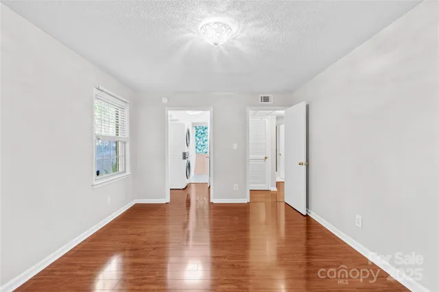 a view of an empty room with window and wooden floor