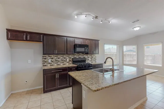 a kitchen with granite countertop stainless steel appliances a sink stove and cabinets