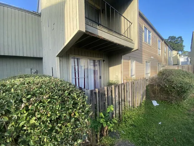 a view of a house with a small yard and wooden floor and fence