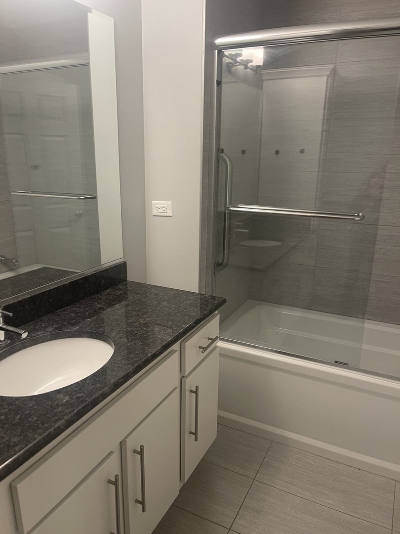 728 North Diamond Lake Road, Unit 211 Mundelein, IL 60060 - Photo 11 of 17 a bathroom with a granite countertop sink a toilet and shower