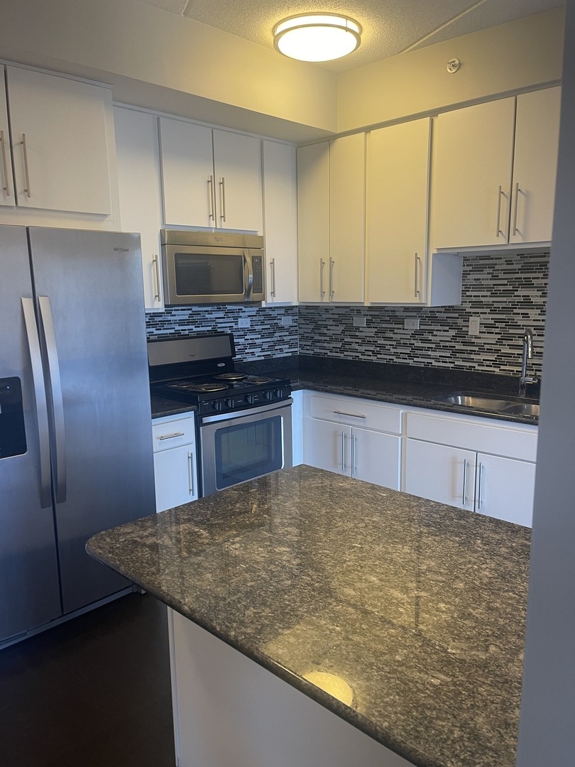 728 North Diamond Lake Road, Unit 211 Mundelein, IL 60060 - Photo 5 of 17 a kitchen with stainless steel appliances granite countertop a sink stove and refrigerator