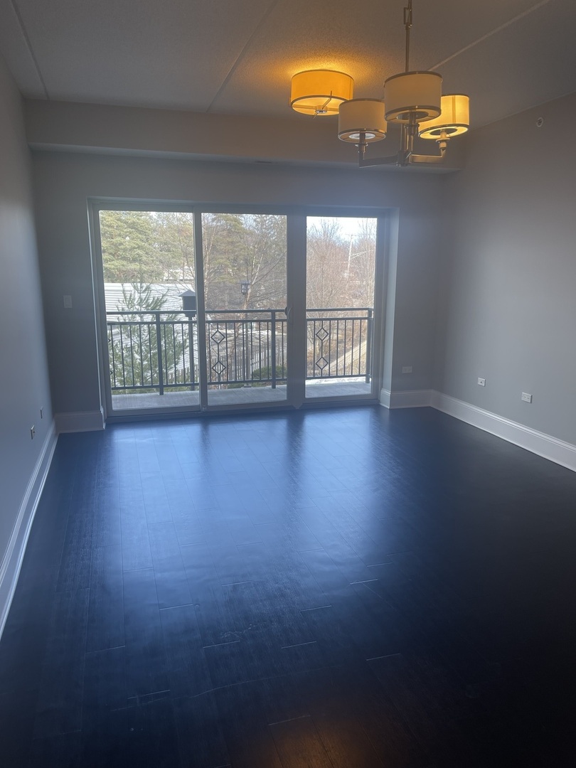 728 North Diamond Lake Road, Unit 211 Mundelein, IL 60060 - Photo 8 of 17 a view of an empty room with wooden floor and a window