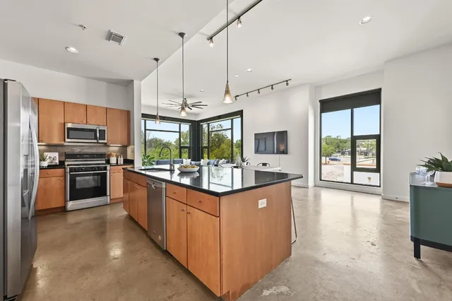 a kitchen with stainless steel appliances kitchen island granite countertop a stove and a refrigerator