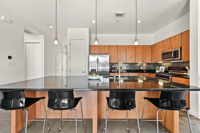 a kitchen with stainless steel appliances a table chairs refrigerator and microwave