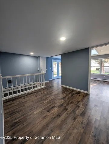 a view of an empty room with wooden floor and staircase