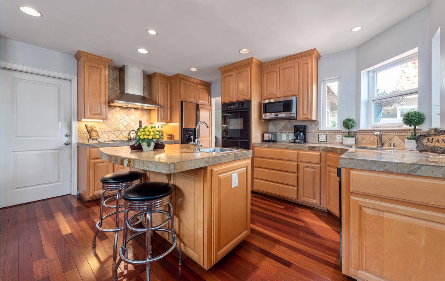 a kitchen with stainless steel appliances a sink a stove a refrigerator cabinets and wooden floor