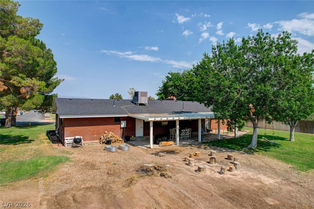 3765 Berkeley Street Logandale, NV 89021 - Photo 86 of 87 A spacious backyard with mature shade trees, a covered patio, and a fire pit area for outdoor enjoyment.