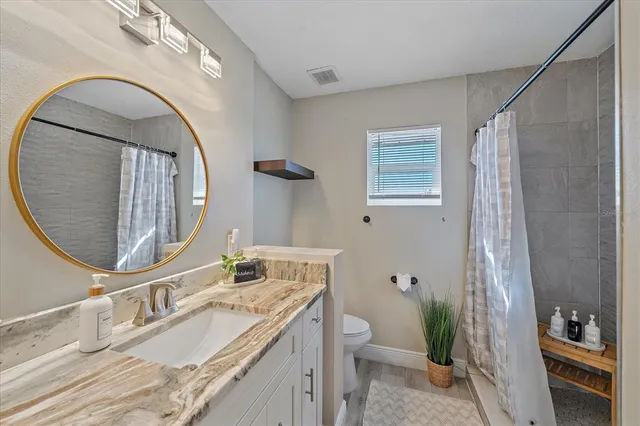a bathroom with a granite countertop toilet a sink and a mirror