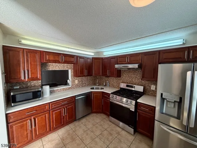 a kitchen with stainless steel appliances granite countertop a refrigerator and a stove top oven