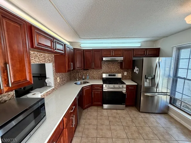 a kitchen with granite countertop a refrigerator and a stove top oven