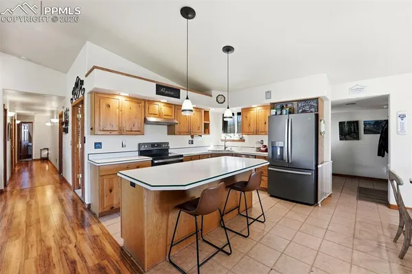 a kitchen with stainless steel appliances a stove a refrigerator a sink dishwasher and a fireplace with wooden floor