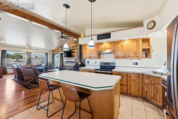 a kitchen with stainless steel appliances a stove a sink a oven a dining table and chairs with wooden floor