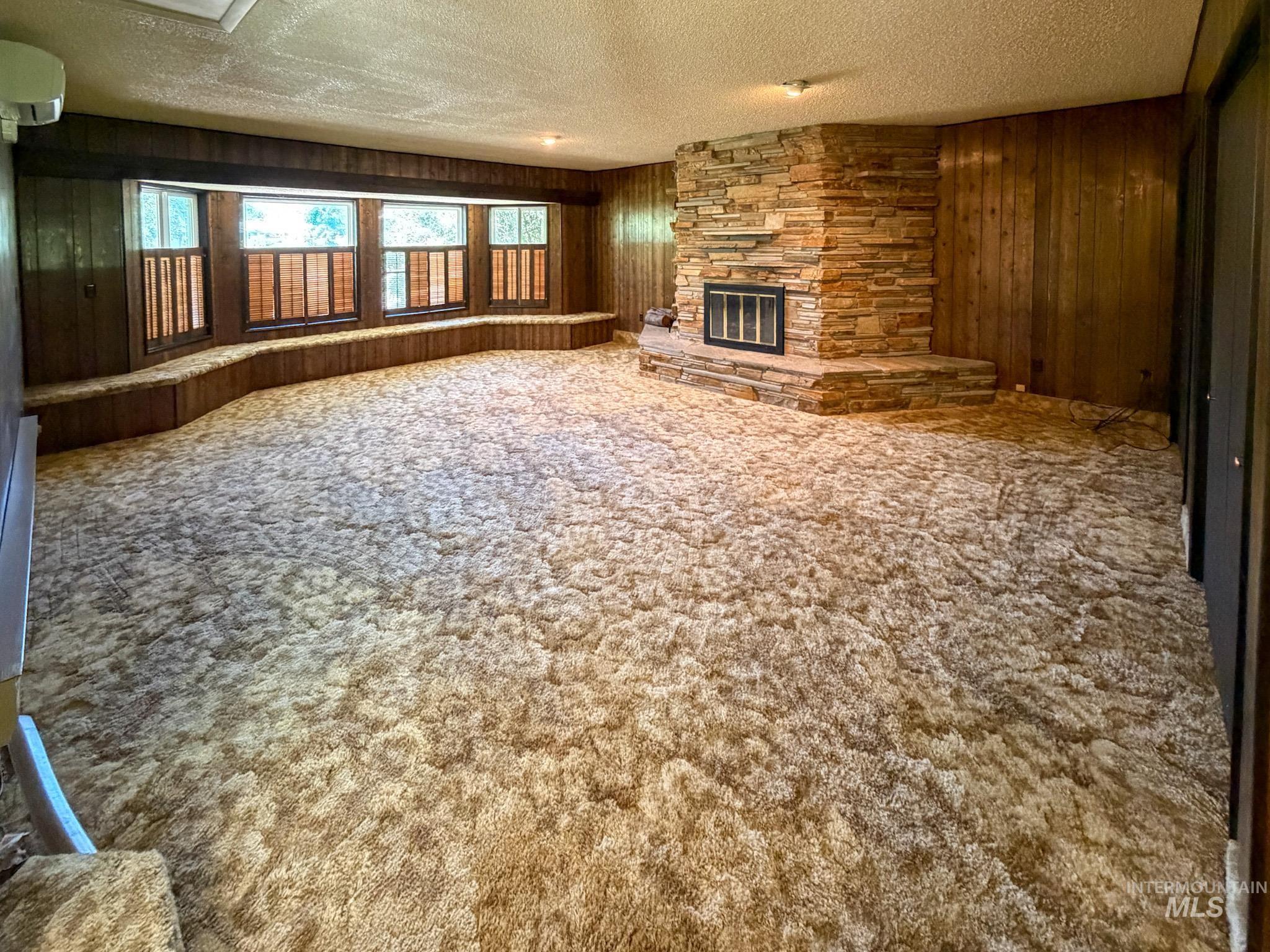 1924 H Street Rupert, ID 83350 - Photo 3 of 13 Spacious room featuring a stone-clad fireplace with a black insert, wood paneling, and an expansive window seat with multiple windows