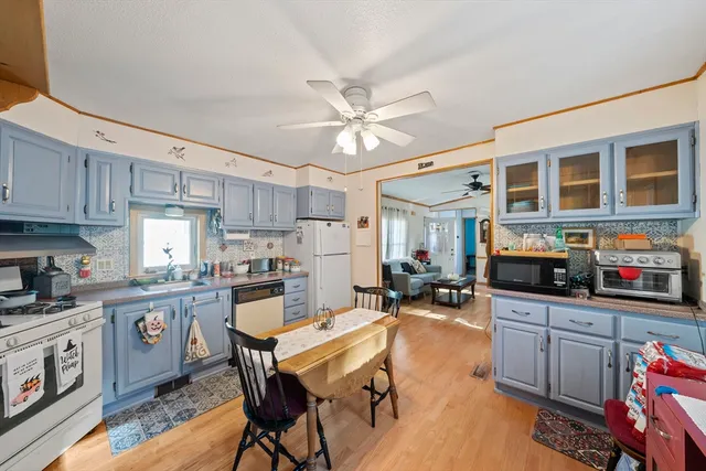 a kitchen with granite countertop a stove a sink dishwasher a dining table and chairs with wooden cabinets