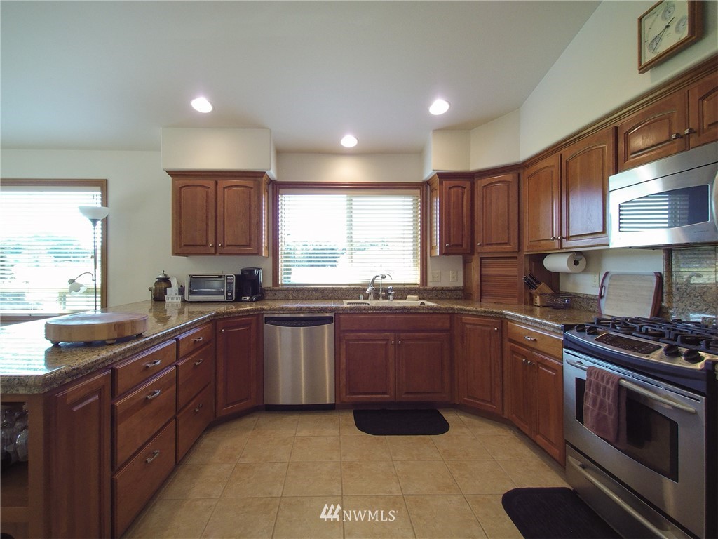 247 Jake Way Sequim, WA 98382 - Photo 7 of 40 a kitchen with stainless steel appliances granite countertop wooden cabinets a stove a sink and a window