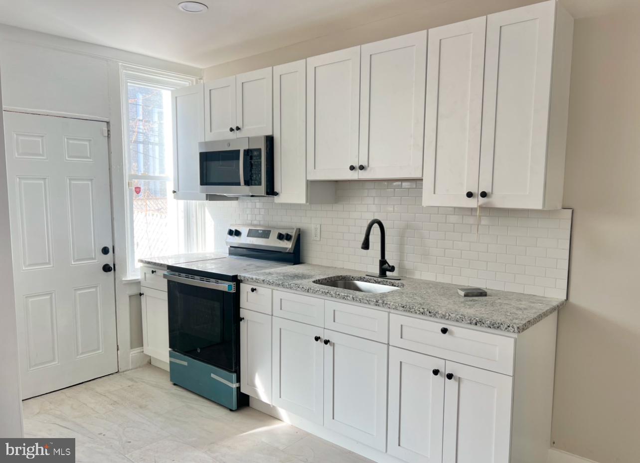 a kitchen with granite countertop white cabinets and sink