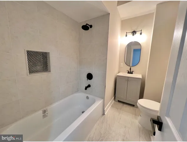 a bathroom with a bathtub sink mirror vanity and toilet