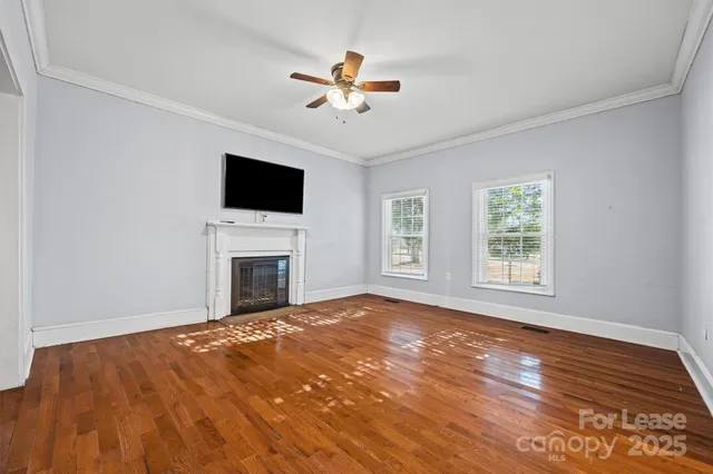a view of a livingroom with a fireplace a ceiling fan and windows