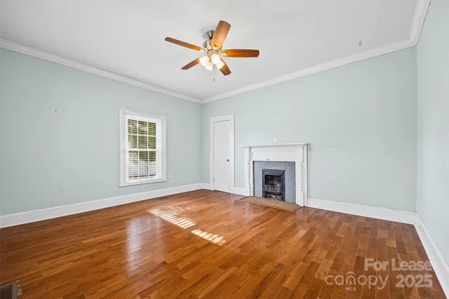 a view of empty room with wooden floor and fireplace