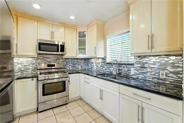 a kitchen with granite countertop white cabinets stainless steel appliances and a sink