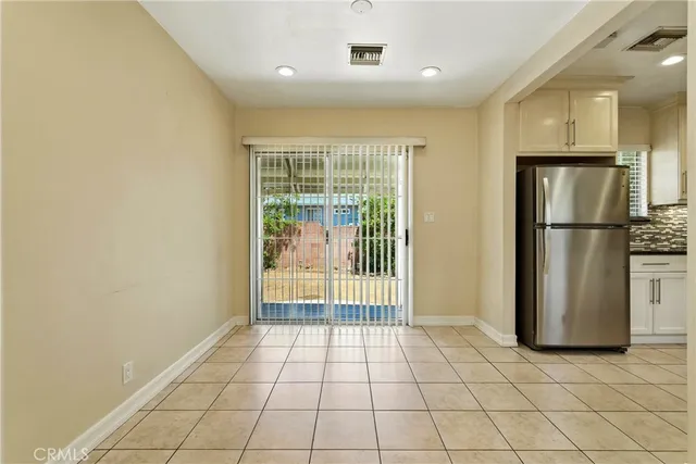 a view of a refrigerator in kitchen and an empty room