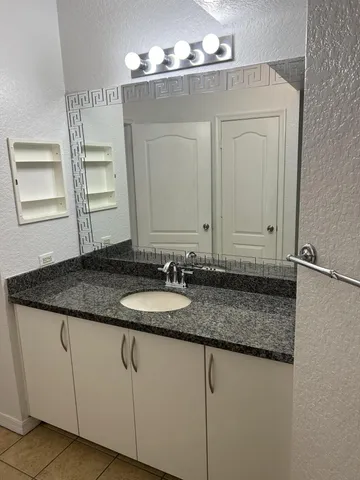 a bathroom with a granite countertop sink and a mirror