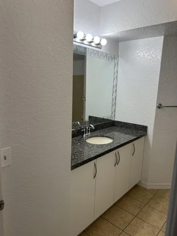 a bathroom with a granite countertop sink and a mirror