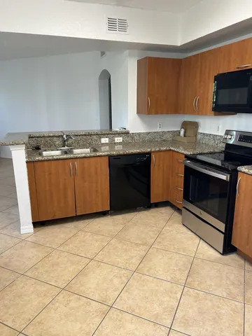a kitchen with granite countertop a stove a sink and a microwave