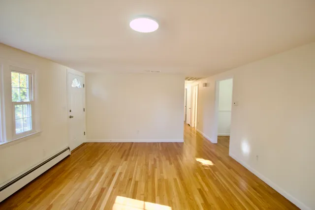 an empty room with wooden floor and windows